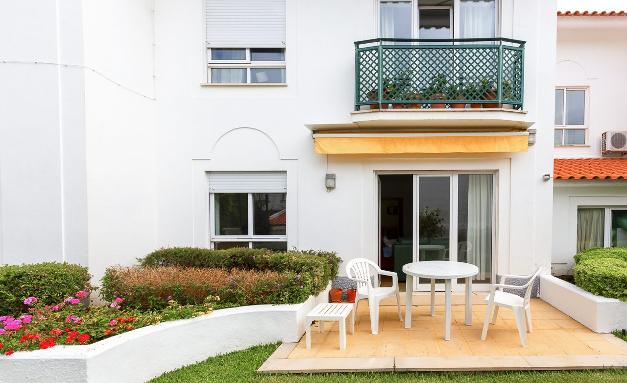 A private ground-floor patio with table and chairs beside the flower beds