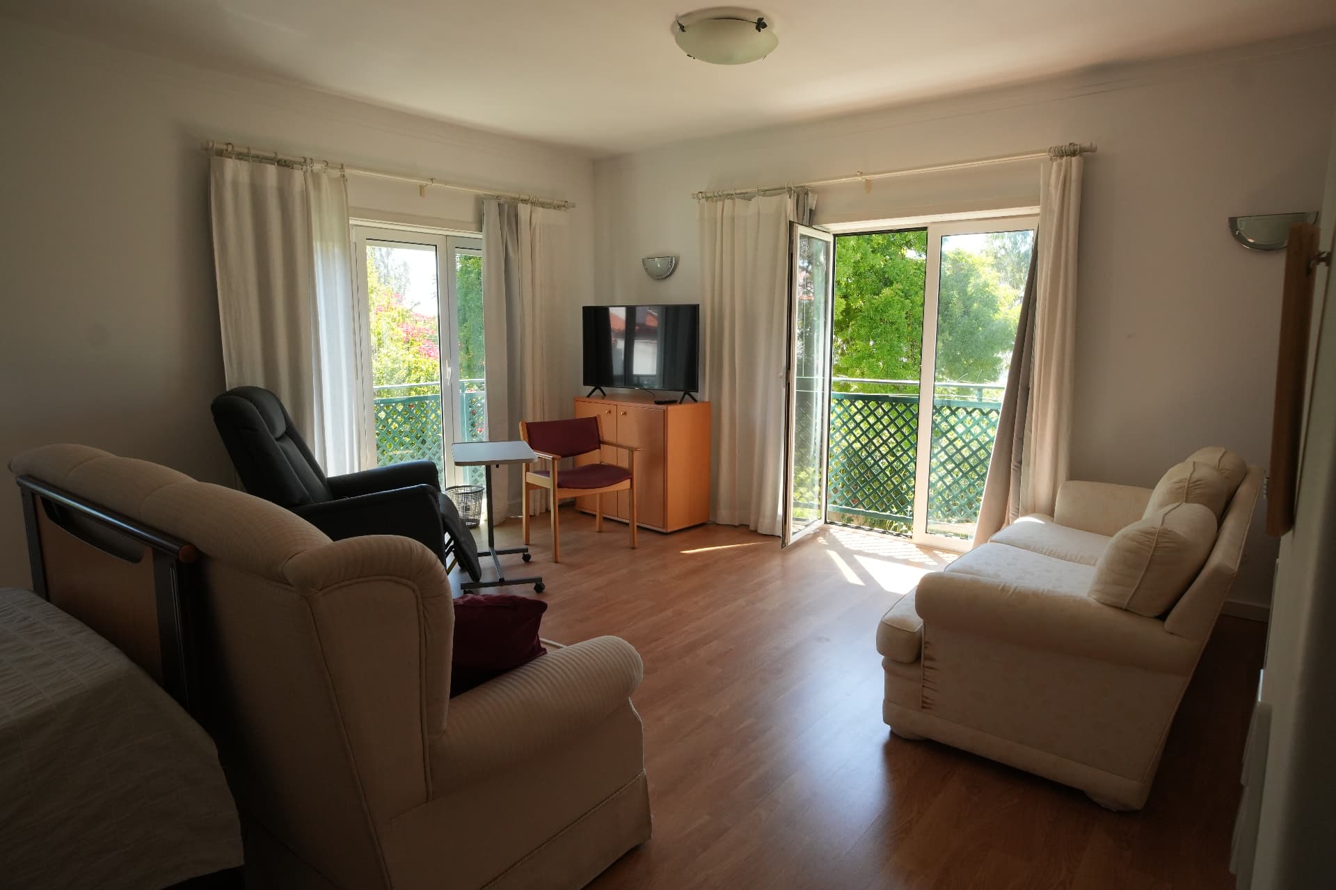 A bright, sunlit studio apartment with garden views and balcony doors