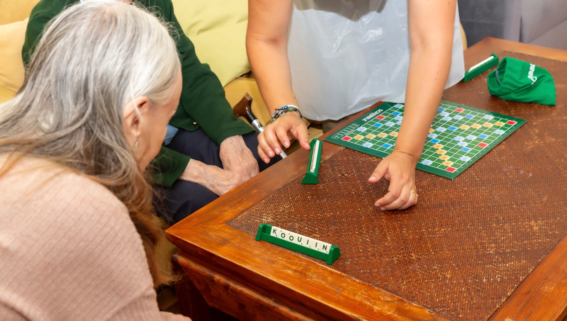 Residents and a staff member playing Scrabble together in the lounge