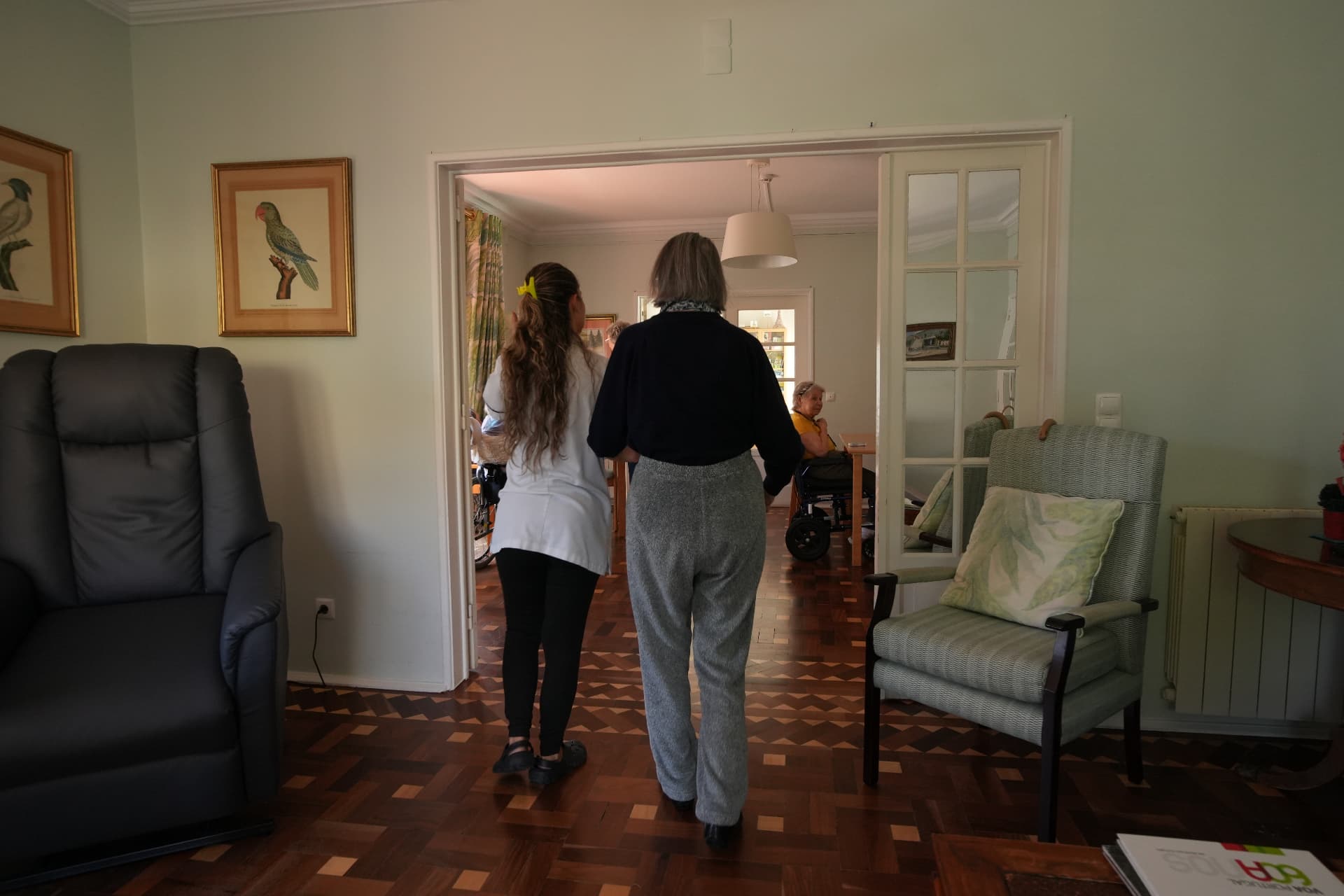 A member of staff walking alongside a resident through the sitting room